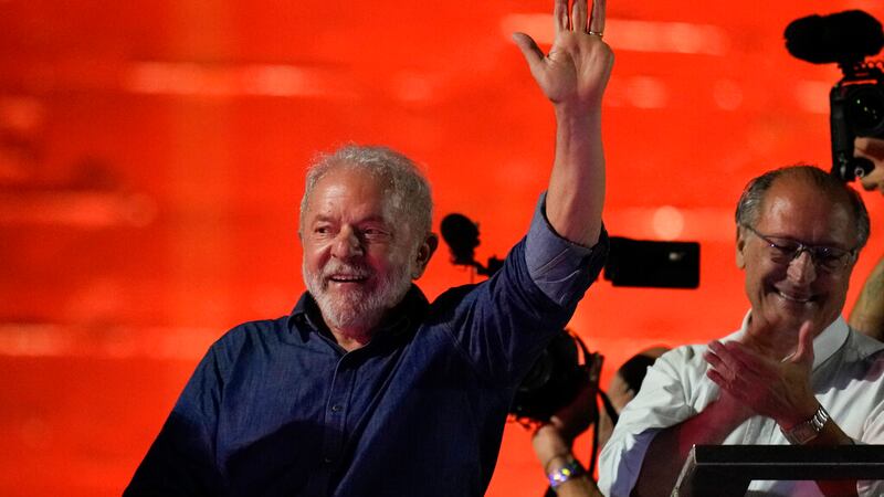 Former Brazilian President Luiz Inacio Lula waves to supporters after he defeated incumbent...