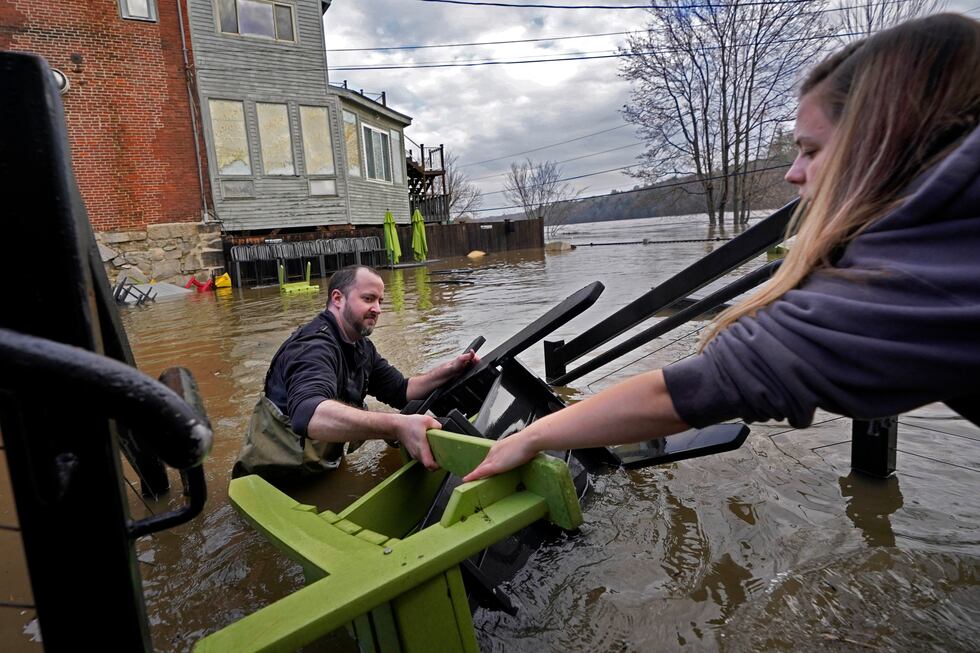 Nathan Sennett hands furniture to Tori Grasse as they work in hip-deep water on the patio of...