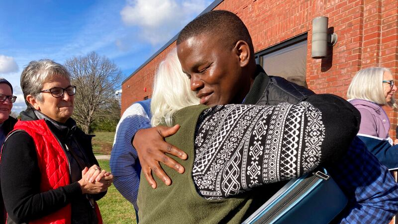 Ugandan refugee Steven Tendo, center top, hugs Dian Kahn, a member of the Central Vermont...